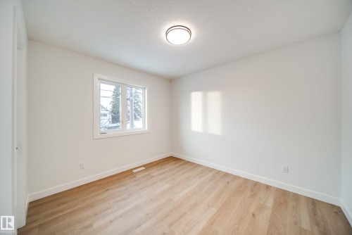 This room features light-toned hardwood flooring, white walls, and a window providing natural light - 9536 148 Street, Edmonton, AB - Indoor Photo Showing Other Room