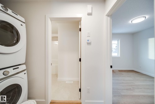 Laundry area featuring a stacked washer and dryer, with a doorway leading to a carpeted space - 9536 148 Street, Edmonton, AB - Indoor Photo Showing Laundry Room