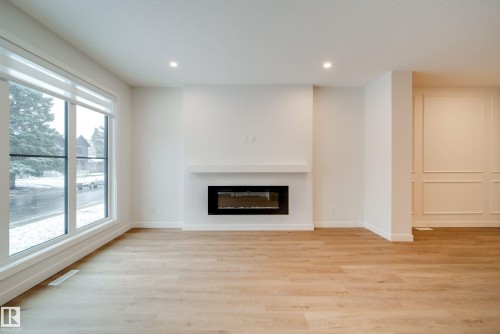 Living area featuring light wood flooring, a fireplace with a mantel, recessed lighting, and large windows with blinds - 9536 148 Street, Edmonton, AB - Indoor With Fireplace