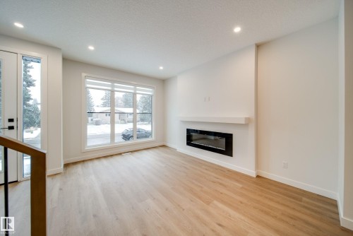 This inviting room features light-colored flooring, a large window providing natural light, and a fireplace with a mantel - 9536 148 Street, Edmonton, AB - Indoor Photo Showing Living Room With Fireplace