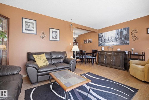 The living area features warm-toned walls and wood-style flooring throughout - 3237 142 Avenue, Edmonton, AB - Indoor Photo Showing Living Room