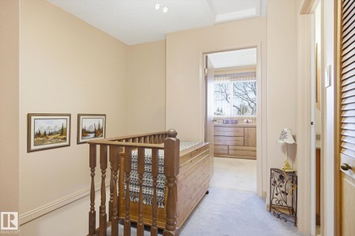 Hallway area featuring light-colored walls, carpeted flooring, and a wooden banister - 3237 142 Avenue, Edmonton, AB - Indoor Photo Showing Other Room