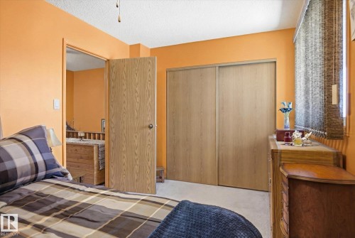 This room features a neutral carpet, wood-look doors, and a window with blinds - 3237 142 Avenue, Edmonton, AB - Indoor Photo Showing Bedroom
