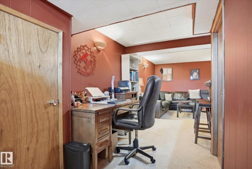 The property features a versatile area with a dedicated workspace, including a desk and a chair, and a separate seating area with a sectional sofa - 3237 142 Avenue, Edmonton, AB - Indoor Photo Showing Office