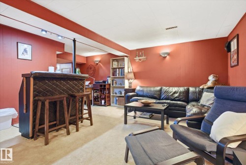 Entertainment area featuring a bar with two bar stools, warm wall paneling, and a carpeted floor - 3237 142 Avenue, Edmonton, AB - Indoor Photo Showing Other Room