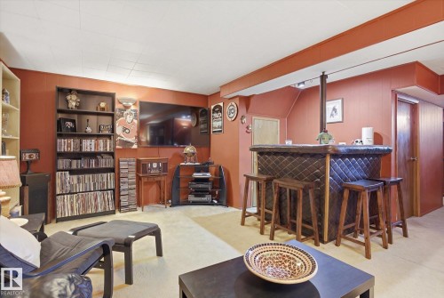 This versatile room features warm wall tones, soft carpeting, and a built-in bar area with seating - 3237 142 Avenue, Edmonton, AB - Indoor