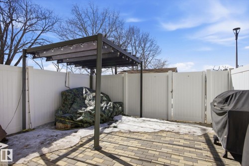 The property features an outdoor patio area with paver stones, a pergola structure, and a privacy fence - 3237 142 Avenue, Edmonton, AB - Outdoor