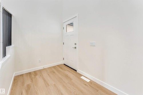 The property features light wood flooring, clean white walls, and a white entry door with a window pane - 91 Dansereau Way, Beaumont, AB - Indoor Photo Showing Other Room