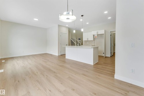 The open concept living area features light-toned flooring, white walls, and recessed lighting - 91 Dansereau Way, Beaumont, AB - Indoor Photo Showing Kitchen