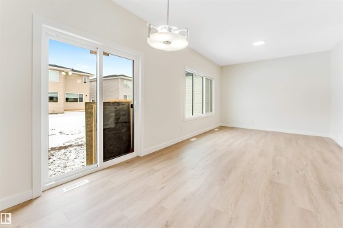 The property features light-colored flooring, white walls, a window providing natural light, and a sliding glass door - 91 Dansereau Way, Beaumont, AB - Indoor Photo Showing Other Room