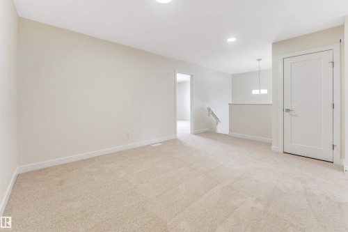 Spacious room featuring neutral carpeting, light-colored walls, and a modern light fixture - 91 Dansereau Way, Beaumont, AB - Indoor Photo Showing Other Room
