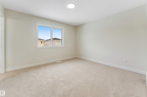 This room features a window providing natural light, a neutral carpeted floor, and a ceiling light fixture - 91 Dansereau Way, Beaumont, AB - Indoor Photo Showing Other Room