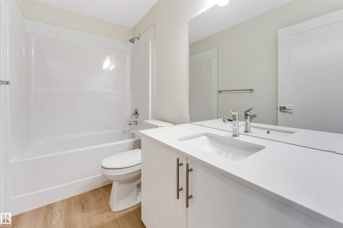 Bathroom featuring a vanity with a white countertop and an undermount sink, a large mirror, a toilet, and a shower/tub combination with white subway tile surround - 91 Dansereau Way, Beaumont, AB - Indoor Photo Showing Bathroom