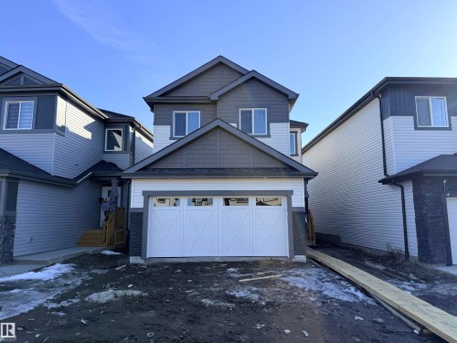 The property features a two-story design with a prominent front-facing garage - 91 Dansereau Way, Beaumont, AB - Outdoor