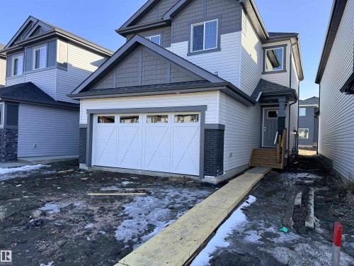 The property features a two-story exterior with light-colored siding and dark grey trim accents - 91 Dansereau Way, Beaumont, AB - Outdoor
