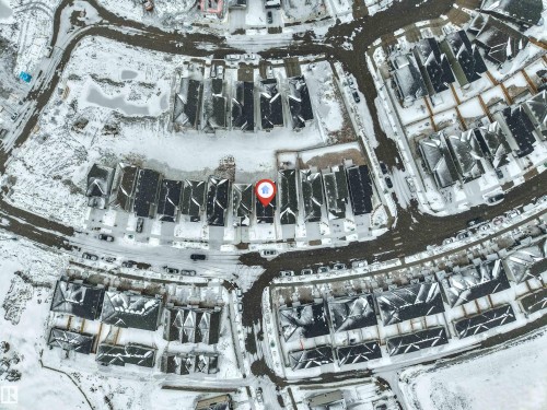 Aerial view of the property and its surrounding area, featuring a residential neighborhood with houses and roads covered in snow - 91 Dansereau Way, Beaumont, AB - 