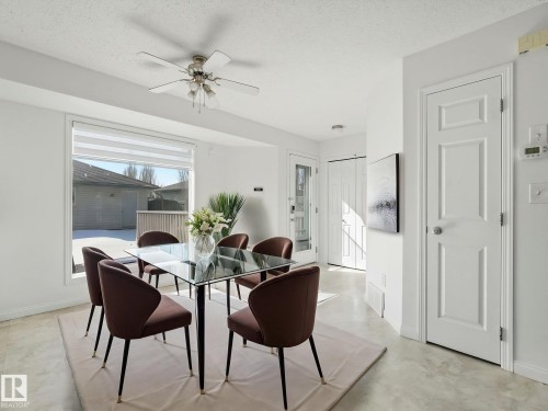 This dining area features a large window with blinds, a ceiling fan with integrated lighting, and light-colored flooring - 675 Mcallister Loop, Edmonton, AB - Indoor Photo Showing Dining Room