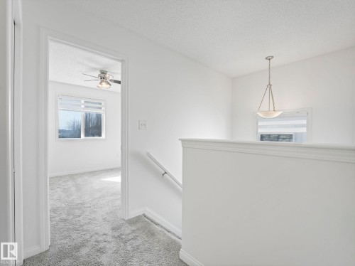 The property features an interior hallway with light-colored carpeting and white walls - 675 Mcallister Loop, Edmonton, AB - Indoor Photo Showing Other Room