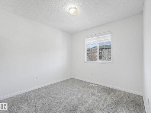 The room features plush carpeting, a window with blinds, and neutral white walls - 675 Mcallister Loop, Edmonton, AB - Indoor Photo Showing Other Room