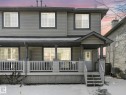 The property features a two-story exterior with grey siding and white-framed windows, complemented by a covered porch with white railings - 675 Mcallister Loop, Edmonton, AB  - Outdoor With Deck Patio Veranda 