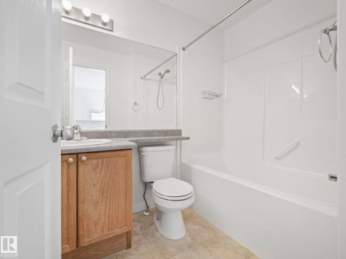 Bathroom featuring a wood vanity with a light-colored countertop, a white toilet, and a white bathtub with a shower - 675 Mcallister Loop, Edmonton, AB - Indoor Photo Showing Bathroom