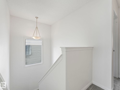 Staircase featuring light gray carpet, white walls, and a window providing natural light - 675 Mcallister Loop, Edmonton, AB - Indoor Photo Showing Other Room