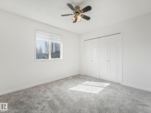 This room features neutral-toned carpeting, a window providing natural light, and a ceiling fan with integrated lighting - 675 Mcallister Loop, Edmonton, AB - Indoor
