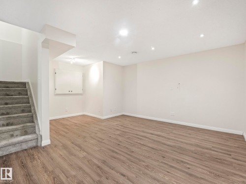 This spacious room features light-toned wood-style flooring, white walls, and recessed lighting - 675 Mcallister Loop, Edmonton, AB - Indoor Photo Showing Other Room