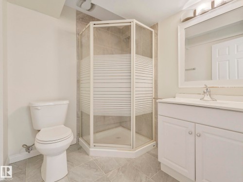Bathroom featuring a corner shower with a glass enclosure, a white vanity with a sink, and a matching toilet - 675 Mcallister Loop, Edmonton, AB - Indoor Photo Showing Bathroom