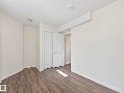 This room features wood-look flooring, white walls, and a white ceiling with a textured finish - 675 Mcallister Loop, Edmonton, AB - Indoor Photo Showing Other Room