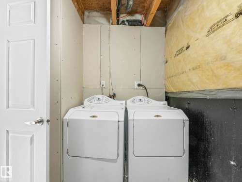 The property includes a dedicated laundry area with a white washing machine and dryer, featuring an exposed ceiling with visible joists - 675 Mcallister Loop, Edmonton, AB - Indoor Photo Showing Laundry Room