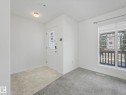 Entryway and living space featuring a white door with glass panels, light-colored tile flooring, and grey carpeting - 675 Mcallister Loop, Edmonton, AB  - Indoor Photo Showing Other Room 
