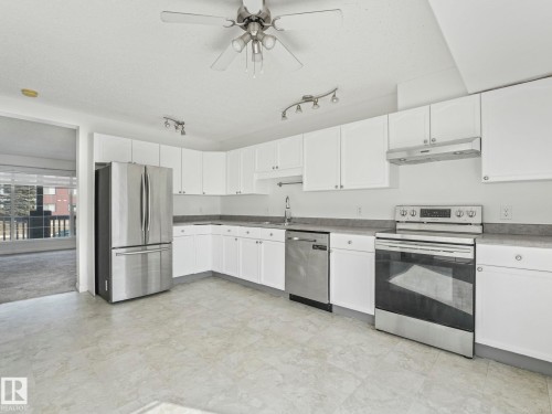 The kitchen features white cabinetry, stainless steel appliances, a ceiling fan, and track lighting - 675 Mcallister Loop, Edmonton, AB - Indoor Photo Showing Kitchen