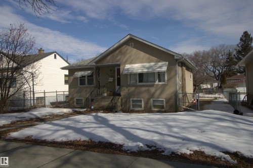 The property features a stucco exterior, a sloped roof, and awnings above the front windows - 12221 94 Street, Edmonton, AB - Outdoor