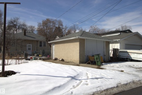 The property features a detached garage with a dark shingle roof and a textured exterior - 12221 94 Street, Edmonton, AB - Outdoor