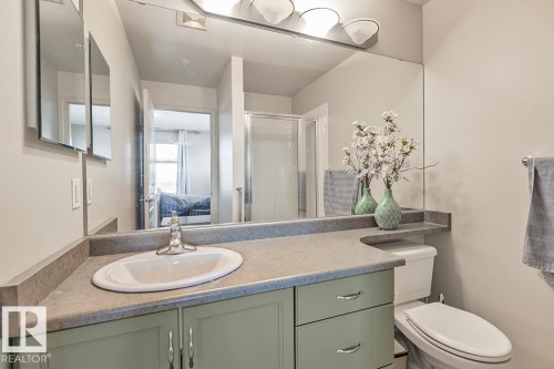 The bathroom features a vanity with a light green base, a light grey countertop, and an integrated white sink - 225 16035 132 Street, Edmonton, AB - Indoor Photo Showing Bathroom