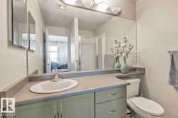 The bathroom features a vanity with a light green base, a light grey countertop, and an integrated white sink - 