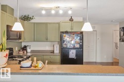 The kitchen features a U-shaped countertop layout, green cabinetry, and a black refrigerator - 