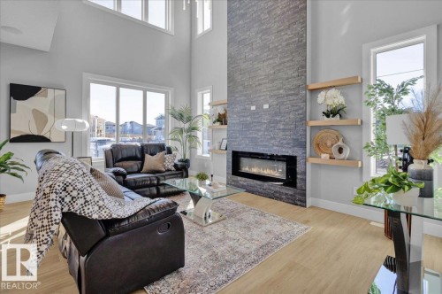 The living area features tall ceilings, light-toned flooring, and large windows that provide abundant natural light - 207 Starling, Fort Saskatchewan, AB - Indoor Photo Showing Living Room With Fireplace