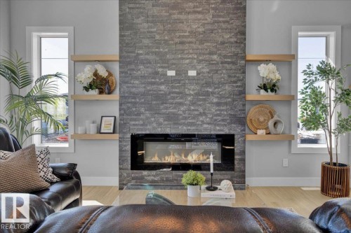 Living room featuring a fireplace with a stone-clad surround, light wood flooring, and light gray walls - 207 Starling, Fort Saskatchewan, AB - Indoor Photo Showing Living Room With Fireplace