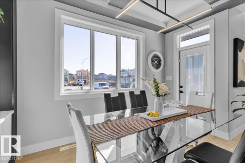 The property features large windows providing natural light, light-colored flooring, and a contemporary ceiling light fixture - 207 Starling, Fort Saskatchewan, AB - Indoor Photo Showing Dining Room