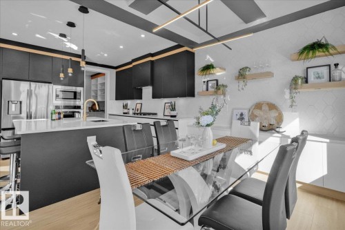 Modern kitchen featuring a large island with seating, stainless steel appliances, and sleek dark cabinetry - 207 Starling, Fort Saskatchewan, AB - Indoor