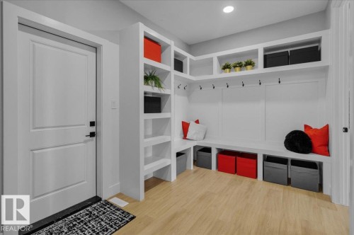 This space features built-in white shelving, a white bench with storage compartments, and hooks for organization - 207 Starling, Fort Saskatchewan, AB - Indoor Photo Showing Other Room