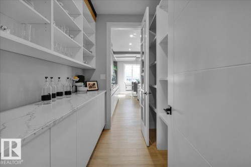 The property features a well-appointed pantry with extensive open shelving and a spacious countertop - 207 Starling, Fort Saskatchewan, AB - Indoor Photo Showing Other Room