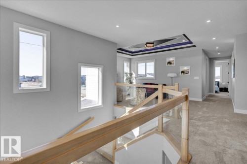 Upper level landing featuring light grey walls, recessed lighting, and a modern stair railing with wood and glass elements - 207 Starling, Fort Saskatchewan, AB - Indoor Photo Showing Other Room