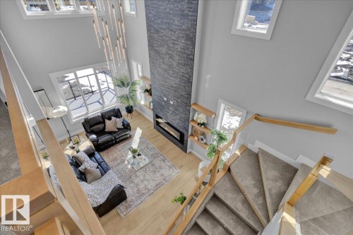 A spacious living area featuring hardwood flooring, a striking floor-to-ceiling stone-faced fireplace, and large windows providing ample natural light - 207 Starling, Fort Saskatchewan, AB - Indoor Photo Showing Other Room