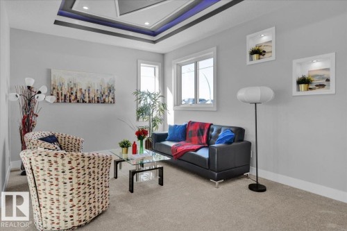 The living area features a coffered ceiling with recessed lighting, light grey walls, and carpeted flooring - 207 Starling, Fort Saskatchewan, AB - Indoor