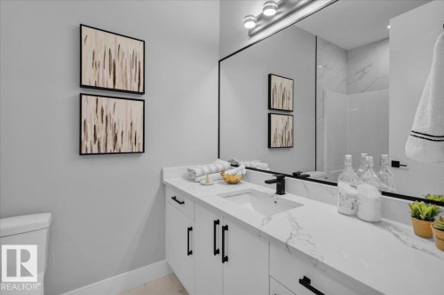The bathroom features a vanity with a white countertop, a rectangular sink, and a black faucet - 207 Starling, Fort Saskatchewan, AB - Indoor Photo Showing Bathroom