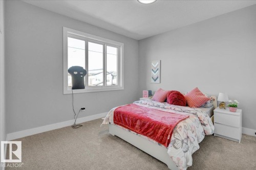 The bedroom features neutral-toned walls, a large window providing natural light, and soft carpet flooring - 207 Starling, Fort Saskatchewan, AB - Indoor Photo Showing Bedroom