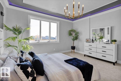 The property features a bright room with light grey walls, carpeted flooring, and a tray ceiling with accent lighting - 207 Starling, Fort Saskatchewan, AB - Indoor Photo Showing Bedroom